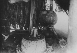 Mani shrine. In the background the pot in which the dawa is prepared. On the altar are wooden sculptures with beaded necklaces and copper rings paid by the initiates to be granted membership. Barambo, Amadi EP.0.0.4192, collection RMCA Tervuren; photo Jospeh Goffinet, s.d.